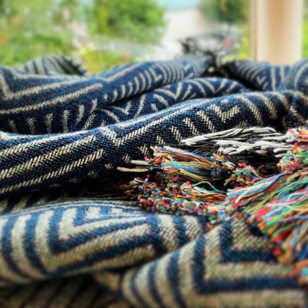 A Close-up shot of the Misty Mountains Throw folded in a rippling fashion on a piece of furniture