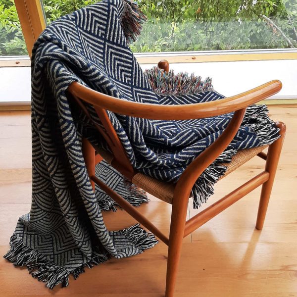 The Misty Mountain Throw draped over a Wishbone Chair