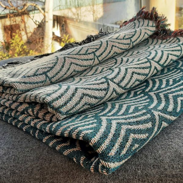 The Shrouded Sea throw neatly folded showing the ombre effect of the pattern