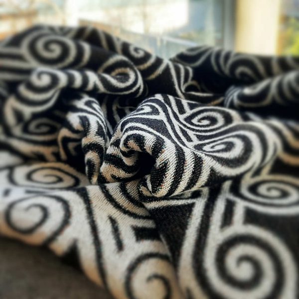 A close-up shot of the Curling Clouds throw casually thrown onto a piece of furniture